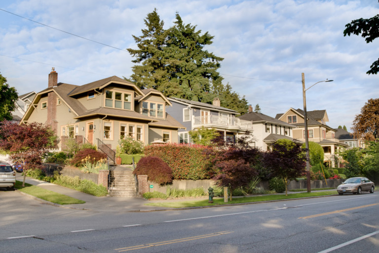 Two-story single family Craftsman style homes in Green Lake neighborhood of Seattle, Washington. Houses are set back from street with mature landscape and sidewalks.