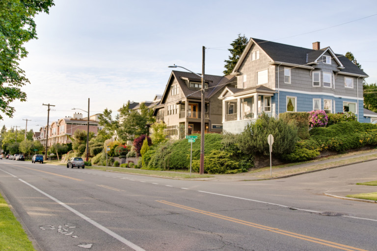 Two-story single family Craftsman style homes in Green Lake neighborhood of Seattle, Washington. Houses are set back from street with mature landscape and sidewalks.