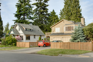 Single family two-story house with two-car garage in Greenwood neighborhood of Seattle, Washington. House has mature landscape on level fenced yard.