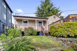 Single family cottage style home in Magnolia neighborhood of Seattle, Washington. House has mature landscape on terraced yard.