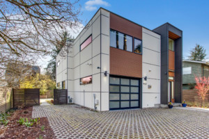 Modern two-story home in Maple Leaf neighborhood of Seattle, Washington. House has large brick driveway and gate around the yard.