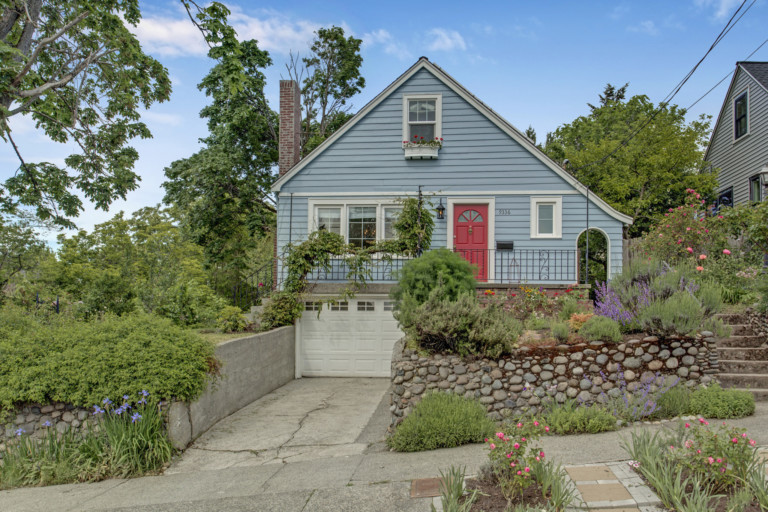Single family bungalow style home in Rainier Beach neighborhood of Seattle, Washington. House has mature landscape on terraced yard.