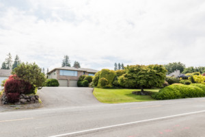 Single family house in Shoreline neighborhood of Seattle, Washington. House has mature landscape on terraced yard.