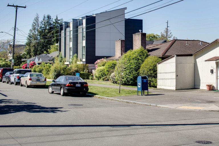 Modern townhouses in Eastlake neighborhood of Seattle, Washington. Complex set back from street with mature landscaping surrounding the building. On-street parking.