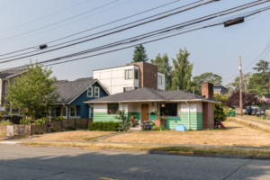 Single family cottage style home in Bryant neighborhood of Seattle, Washington. House is set back from street on level lot with sidewalk in front and side.