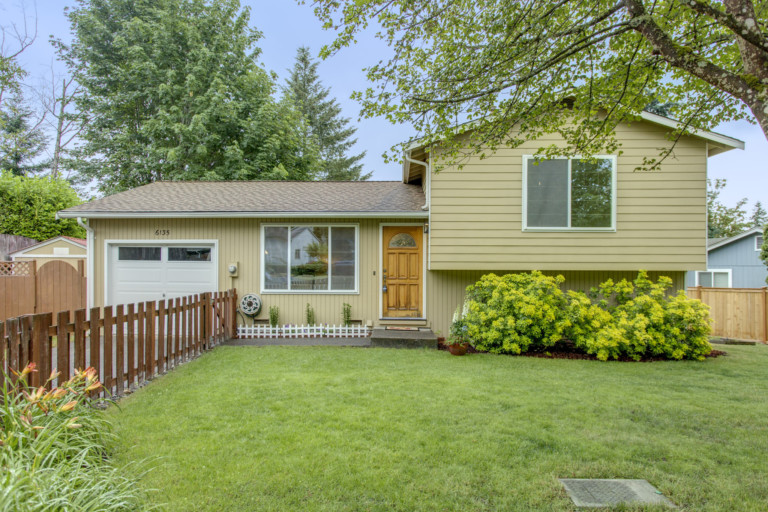 Single family split-level house in Kenmore-Lake Forest Park neighborhood of Seattle, Washington. House has mature landscape on level fenced yard.