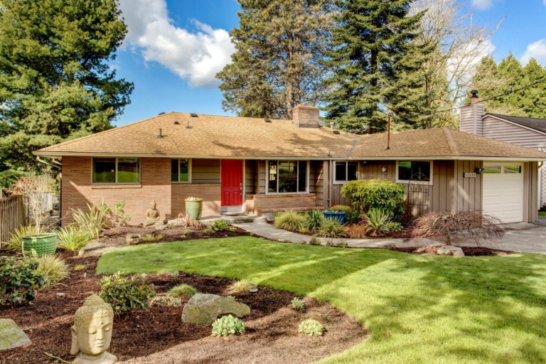 Mid-century modern rancher style single family home in Meadwbrook neighborhood of Seattle. House has mature landscape on level yard.