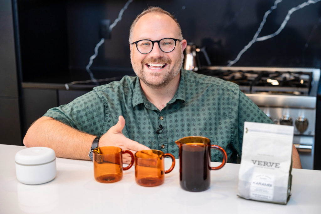 Roy showing off coffee in a kitchen with two mugs placed in front of him